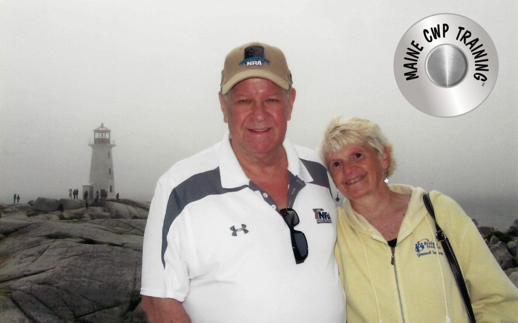 A smiling couple posing indoors by a white wall.